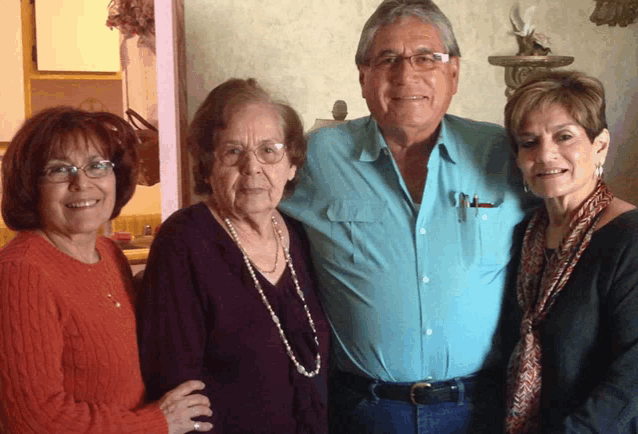 a man in a blue shirt is standing with two women