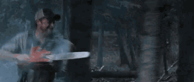 a man is using a chainsaw to cut a tree trunk in the woods .