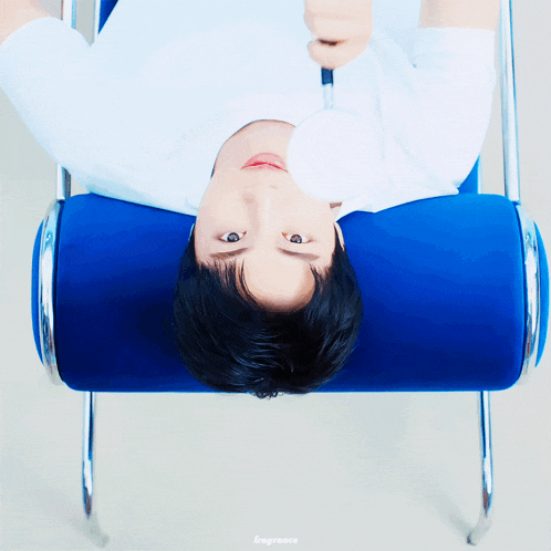 a man in a white shirt is laying on a blue chair with his head down