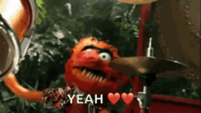 a muppet is playing drums and saying yeah with hearts