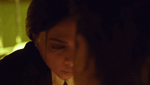 a woman in a suit and tie is looking at another woman 's face