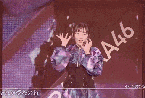 a woman in a blue jacket is dancing on a stage with a microphone .