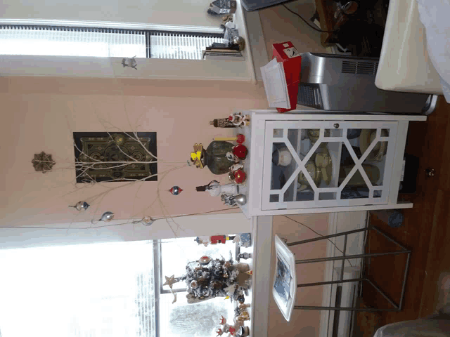 a christmas tree sits in front of a window with a clock on the wall