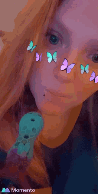 a woman with butterflies on her face and a momento logo