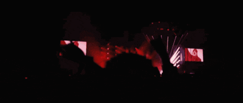 a crowd of people at a concert with their hands up in the air