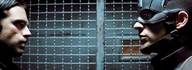 two men are looking at each other in front of a fence
