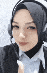 a woman wearing headphones and a hijab is smiling .