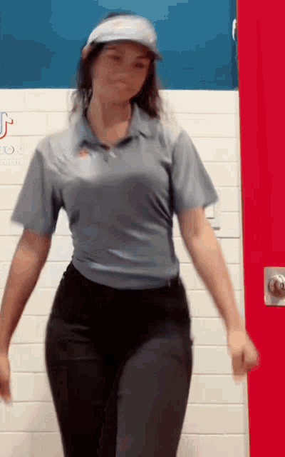 a woman in a blue shirt and black pants is dancing in a room .