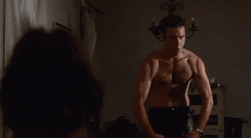 a shirtless man stands in front of a woman