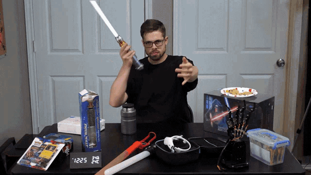 a man is holding a lightsaber in front of a star wars box
