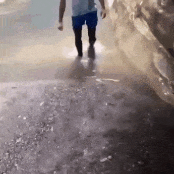a man in blue shorts is walking through a puddle of water