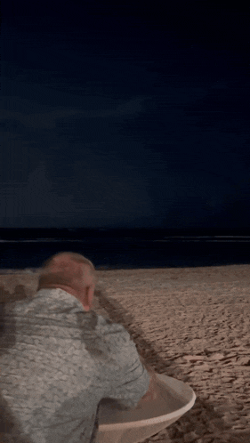 a blurry picture of a man sitting at a table on a beach at night