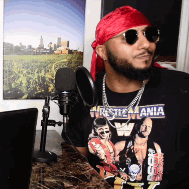 a man wearing a wrestlemania t-shirt is standing in front of a microphone