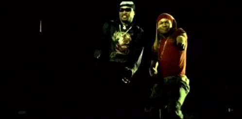 a couple of men are standing next to each other in the dark .