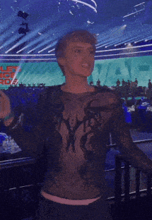 a woman wearing a black shirt with a cross on it is dancing on a stage