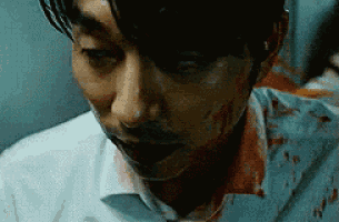 a close up of a man 's face with blood on his collar .