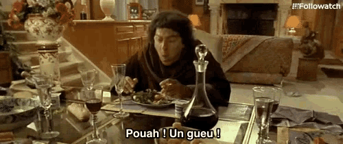 a man is sitting at a table with a plate of food and a glass of wine and says pouah un gueu