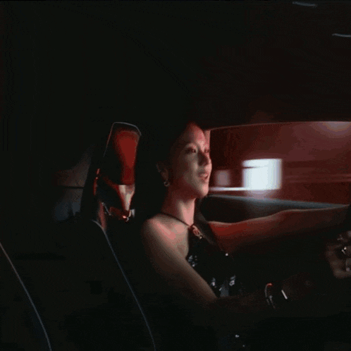 a woman in a black dress sits in a car