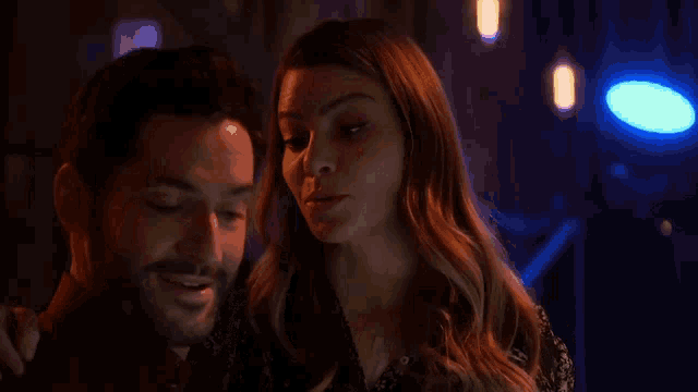 a man and a woman are standing next to each other in a dark room with blue lights .