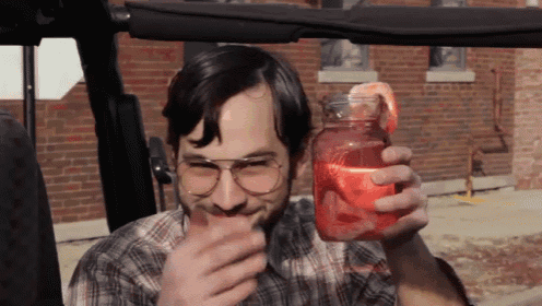 a man wearing glasses is holding a mason jar with shrimp on it