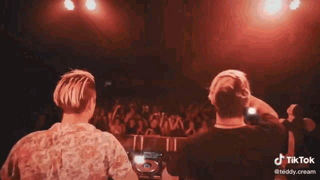 two men are playing music on stage in front of a crowd .