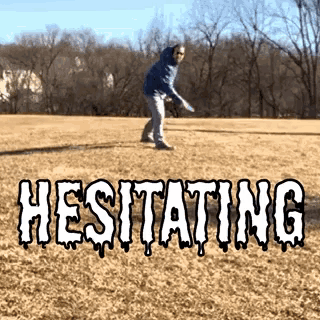 a man is throwing a frisbee in a field with the word hesitating written in white