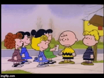 a group of peanuts cartoon characters are standing on a sidewalk .