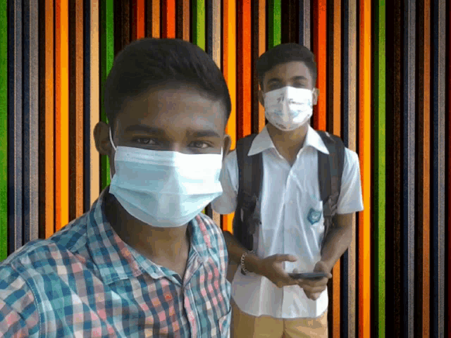 two young men wearing face masks are posing for a photo