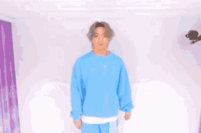 a man in a blue sweater is standing with his arms outstretched .