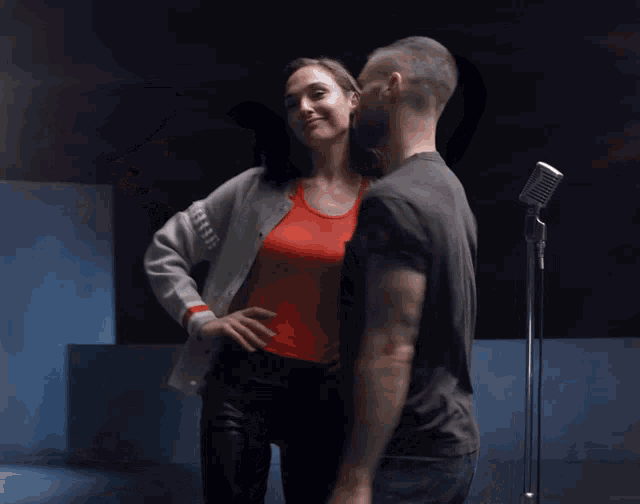 a man and a woman are dancing in front of a microphone in a dark room