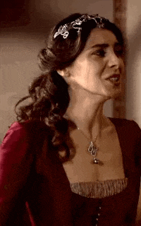 a woman in a red dress is wearing a necklace and a headband .