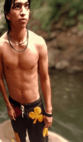 a shirtless young man wearing black shorts with a yellow shamrock on the side