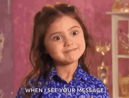 a little girl is wearing a blue shirt and making a funny face .
