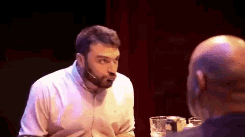 a man with a microphone in his mouth is talking to another man .