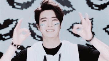 a young man with a sticker on his face is making an ok sign .