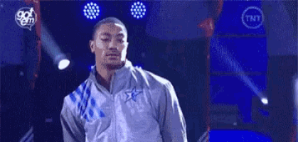 a man in a gray jacket is standing on a stage in front of a blue background .