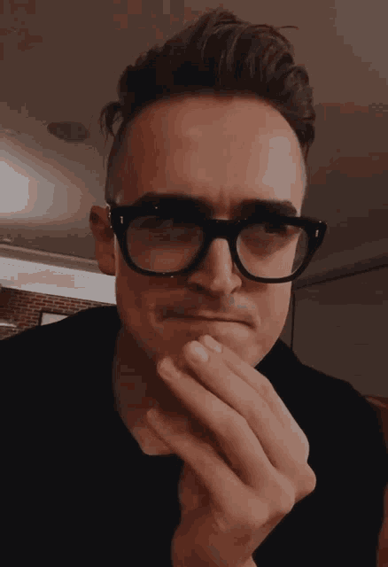 a man wearing glasses holds his hand to his mouth