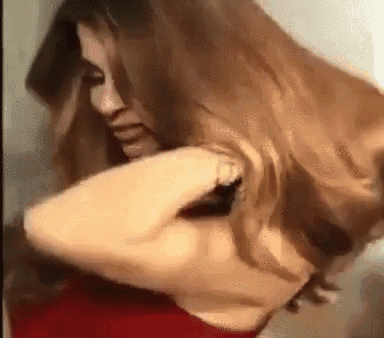a woman in a red dress is holding her hair in her hand .