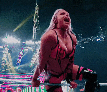 a woman in a bikini is holding a sword and screaming in a ring