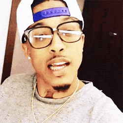 a man wearing glasses and a hat is taking a selfie