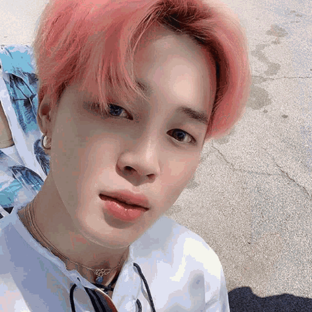 a young man with pink hair is wearing a white shirt with palm trees on it