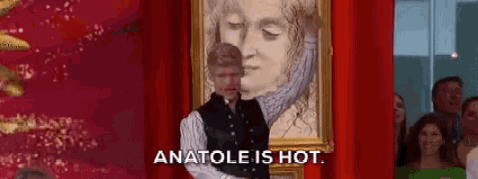 a man is standing in front of a framed painting of a woman .