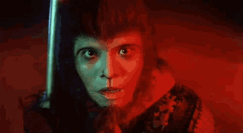 a close up of a person 's face holding a sword