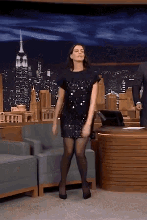 a woman in a black dress is dancing in front of a cityscape
