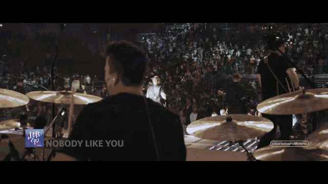 a man sings into a microphone while playing a guitar in front of a screen that says let 's go '