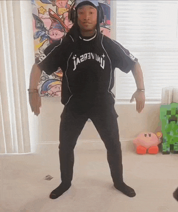 a man wearing headphones and a black t-shirt is standing in a room .