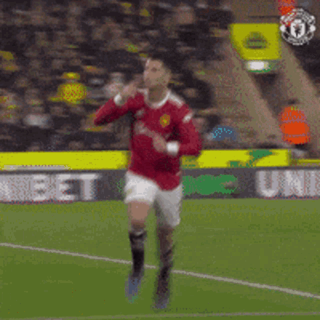 a man in a red shirt is running on a soccer field in front of an unibet sign