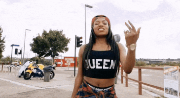 a woman wearing a queen crop top is giving the middle finger