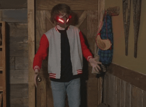 a man wearing a red and gray jacket is standing in front of a door