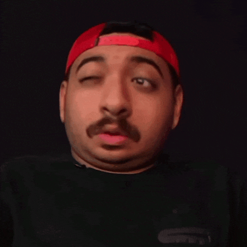 a man with a mustache wearing a red hat and a black shirt
